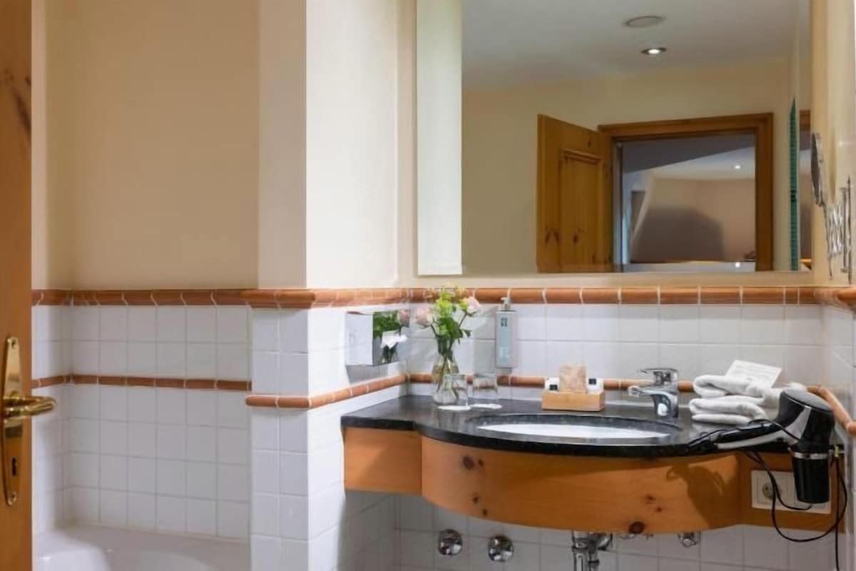 A bathroom with a wooden vanity, a sink, a mirror, and a towel rack.