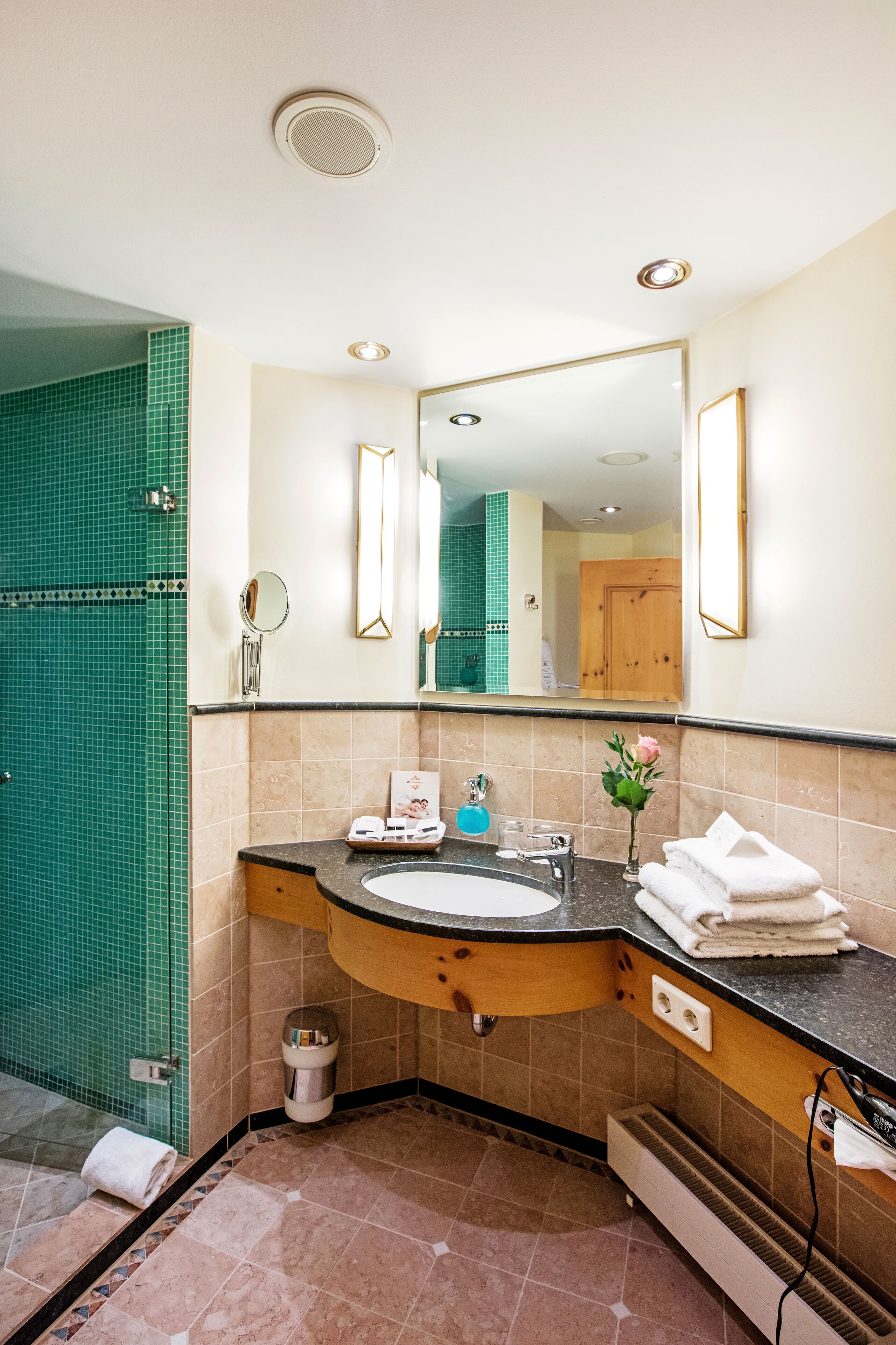 A bathroom with a sink, mirror, and shower area.