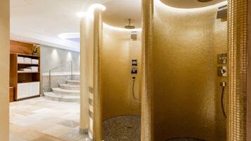 A modern bathroom with a circular shower area, marble flooring, and a wooden vanity with towels.