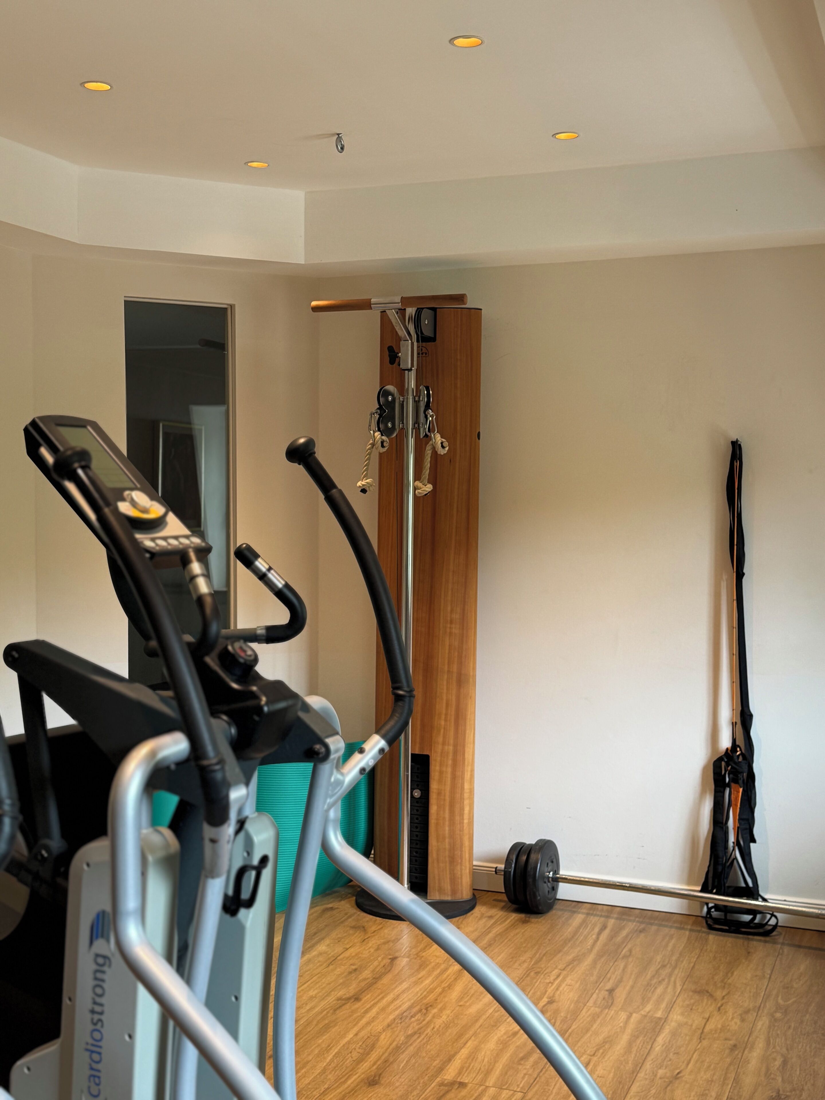 A gym with cardio equipment, a pull-up bar, and a mirror.