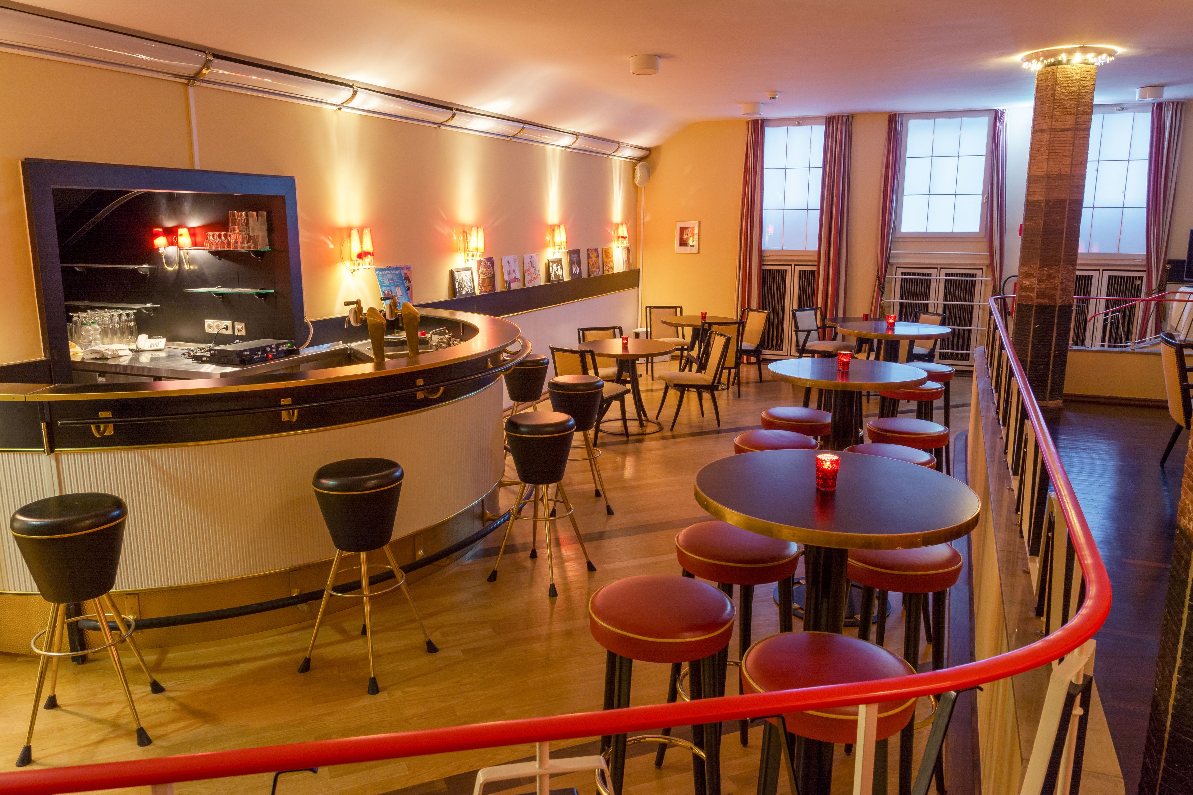 A bar area with stools, tables, and a counter.
