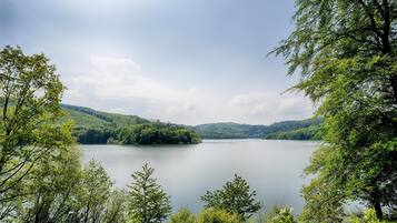 Ein See, umgeben von üppigen grünen Hügeln und Bäumen.