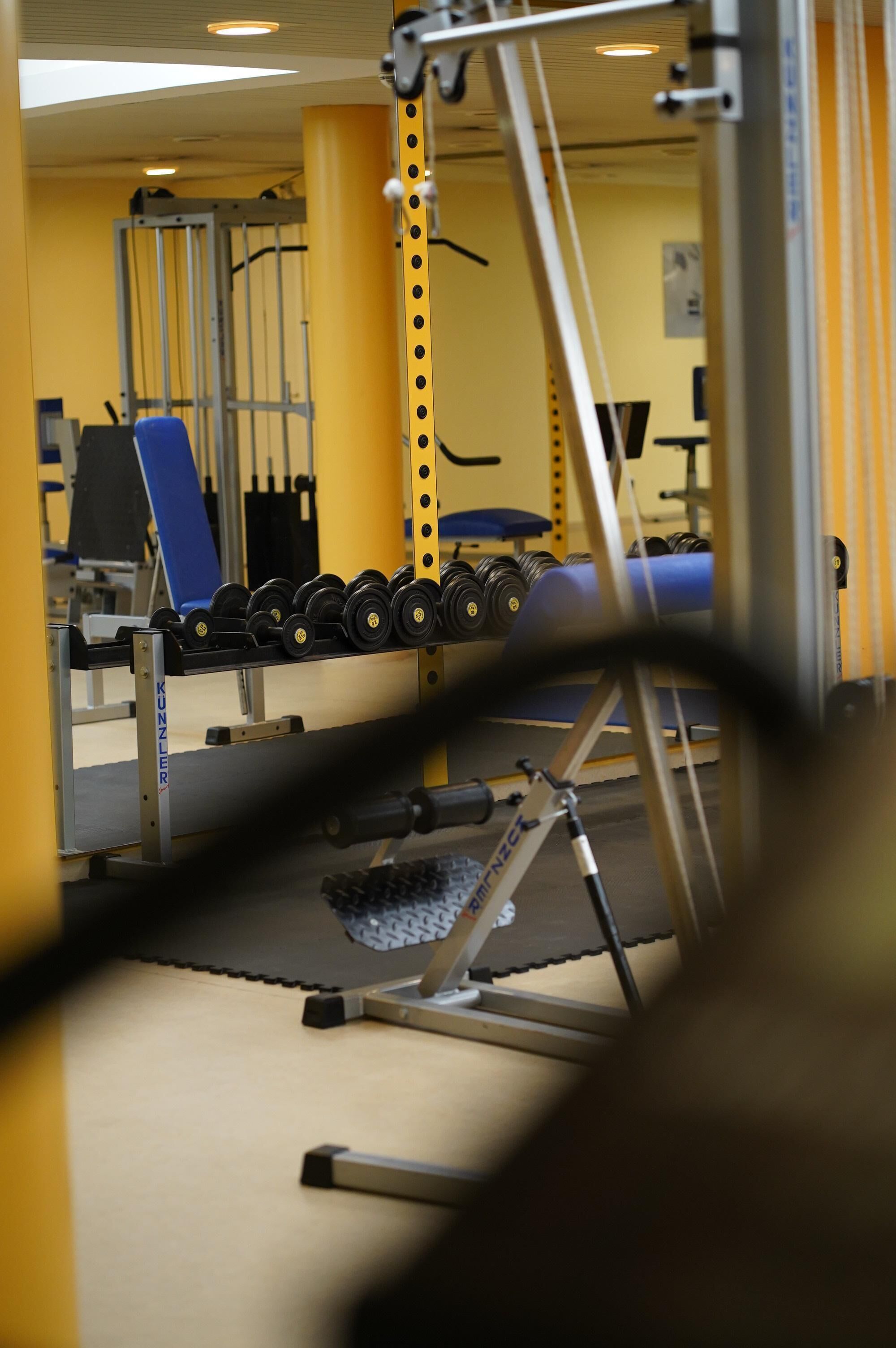 A gym with weightlifting equipment, including dumbbells and a bench.