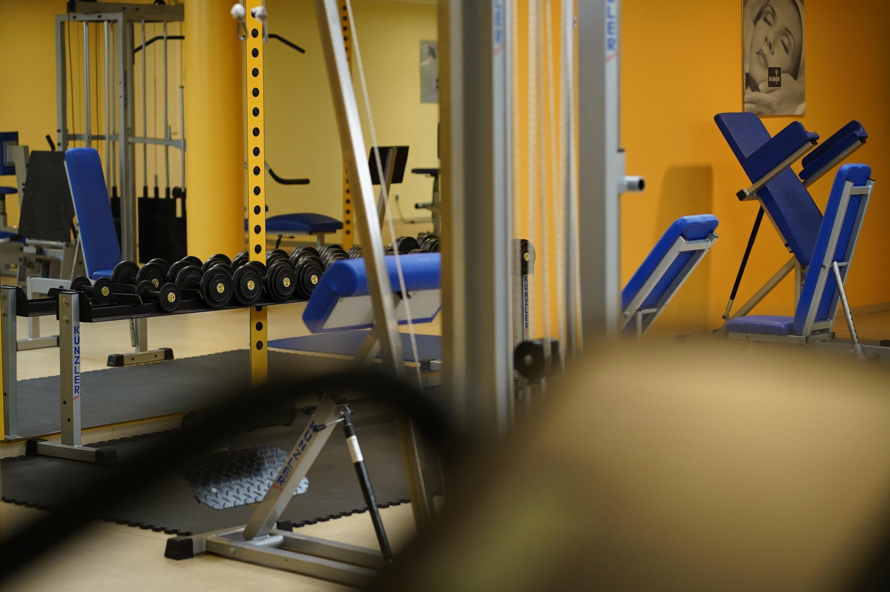 Ein Fitnessstudio mit Trainingsgeräten, darunter Kurzhanteln und Kraftgeräte.