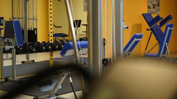 Ein Fitnessstudio mit Trainingsgeräten, darunter Kurzhanteln und Kraftgeräte.
