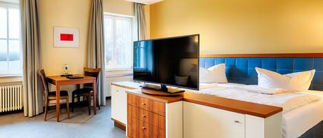 A hotel room with a bed, a television, a desk, and a chair.