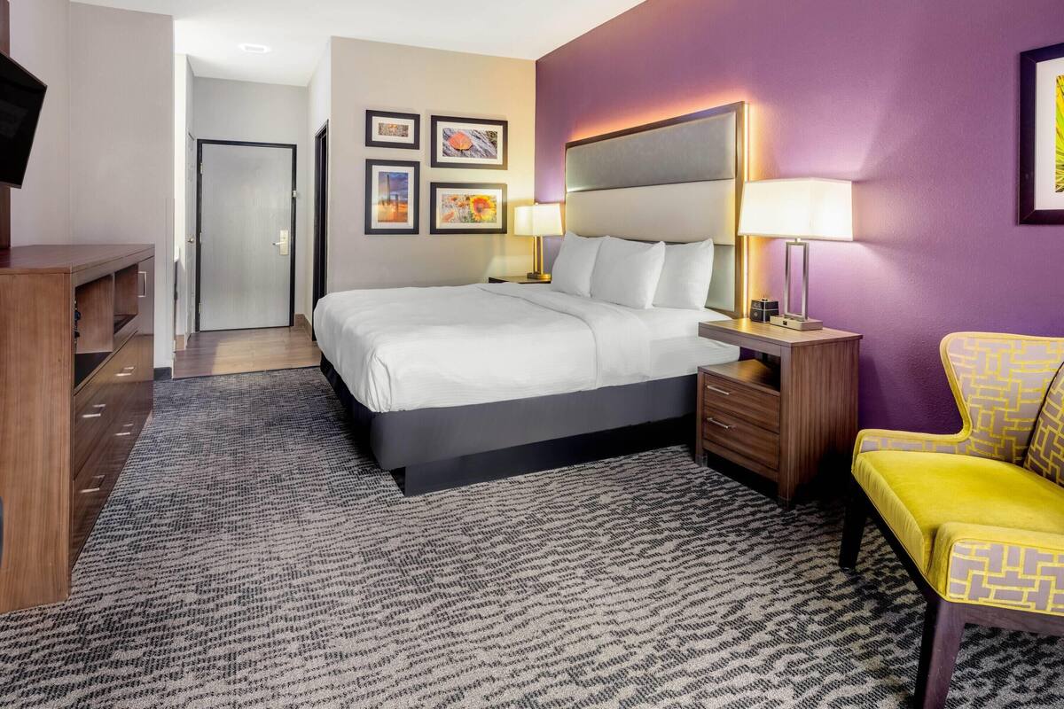Une chambre d’hôtel comprenant un lit, des tables de chevet, un bureau, une chaise et des œuvres d’art accrochées aux murs.