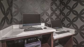 A workspace with two monitors, keyboards, and a Brother printer on a white desk against a patterned wall.