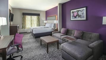 A hotel room with a bed, a sofa, a desk, and a chair.