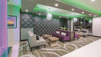 A modern hotel lobby with a seating area, patterned walls, and ambient lighting.