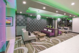 Un hall d’hôtel moderne doté d’un espace salon, de murs aux motifs originaux et d’un éclairage d’ambiance.
