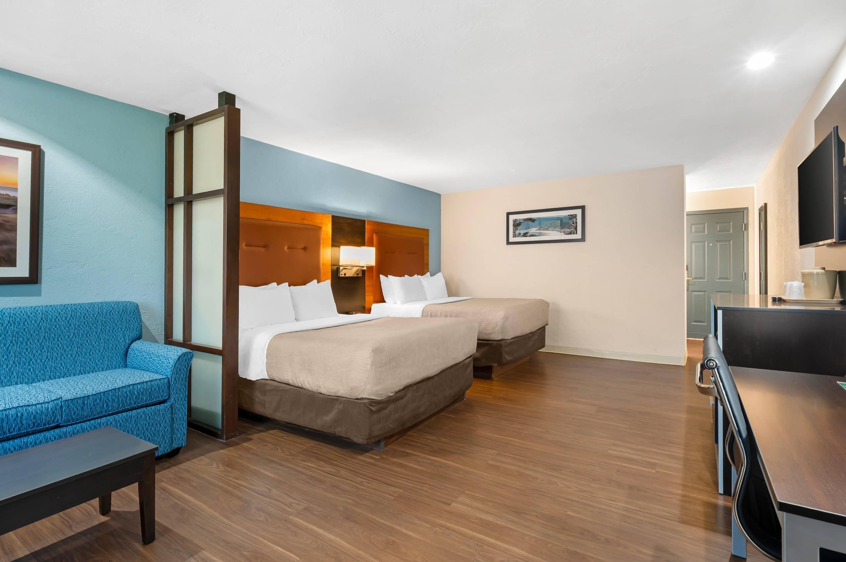 A hotel room with a bed, a sofa, a desk, and a television.