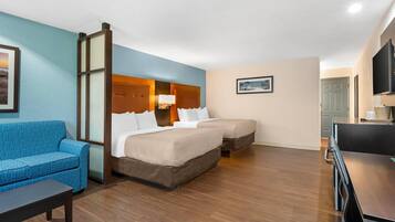 A hotel room with a bed, a sofa, a desk, and a television.