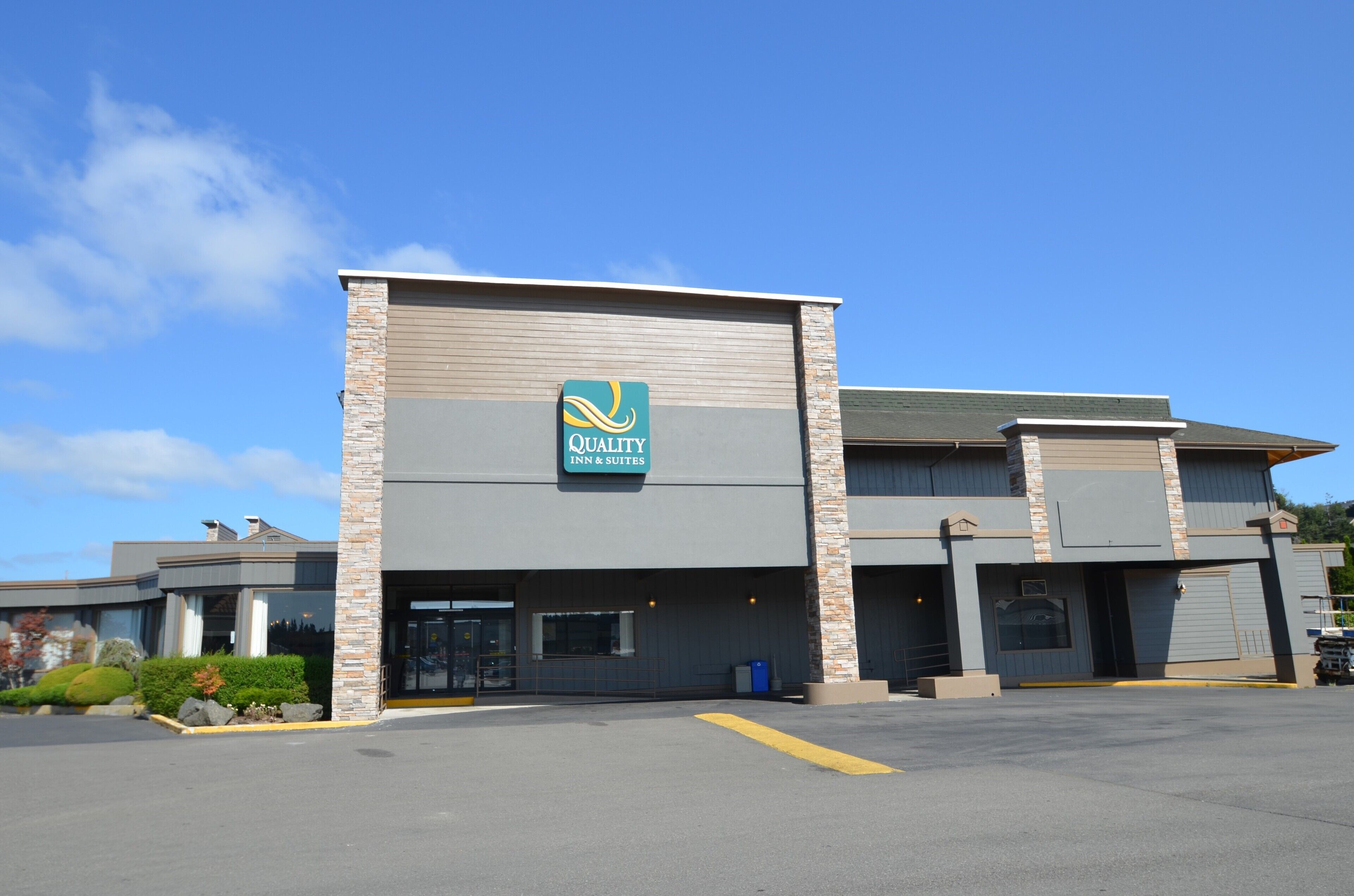 A Quality Inn & Suites building with a modern design, featuring a prominent logo and a parking lot in front.