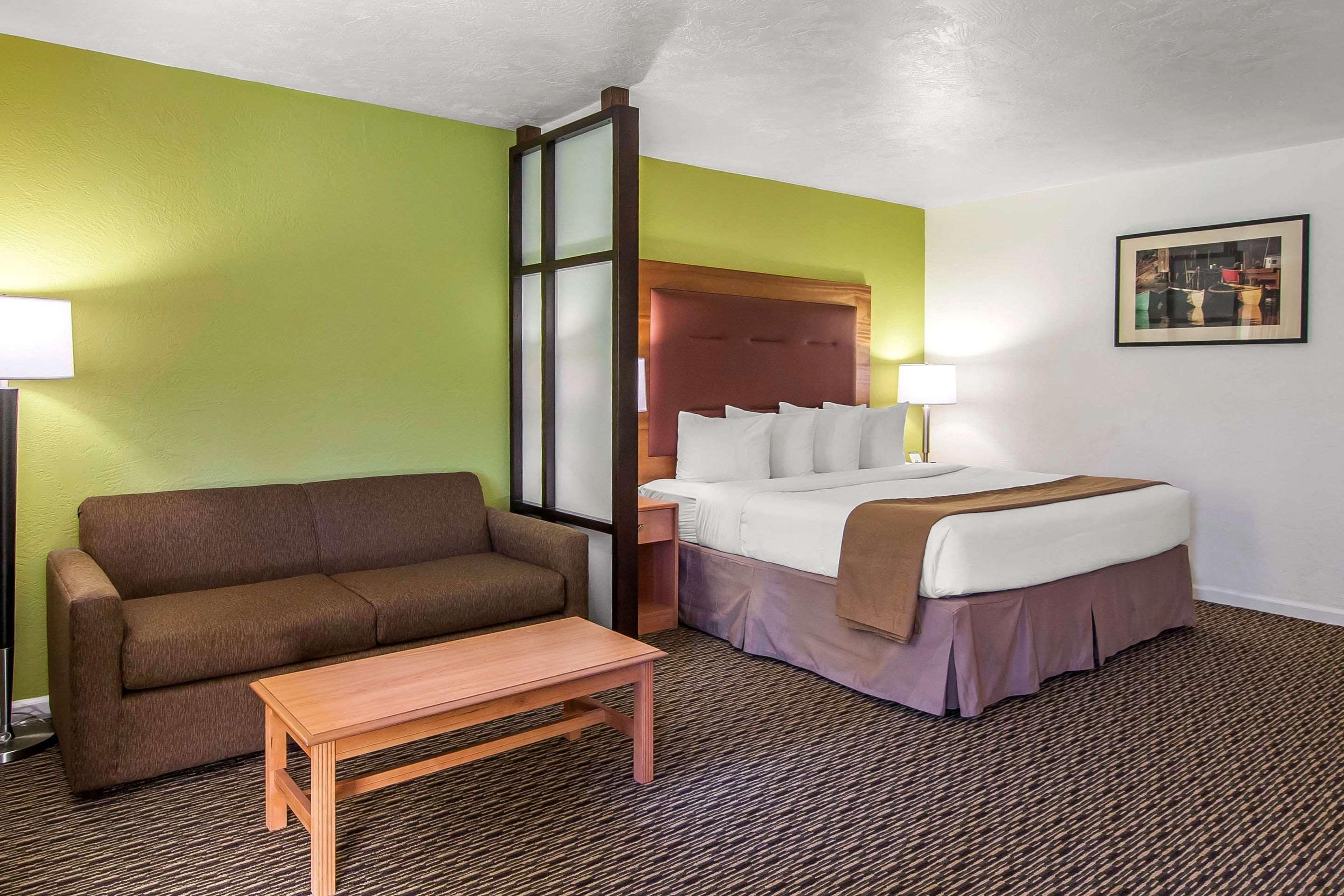A hotel room with a bed, a sofa, a table, and a nightstand.