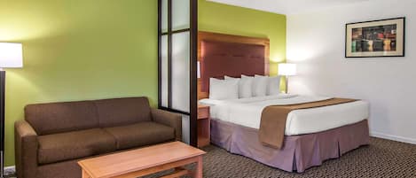 A hotel room with a bed, a sofa, a table, and a nightstand.