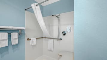 A shower with a grab bar, a white toilet, and a towel rack with towels.