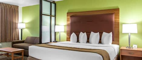 Une chambre d’hôtel avec un grand lit, un canapé, un bureau et une fenêtre avec des rideaux.
