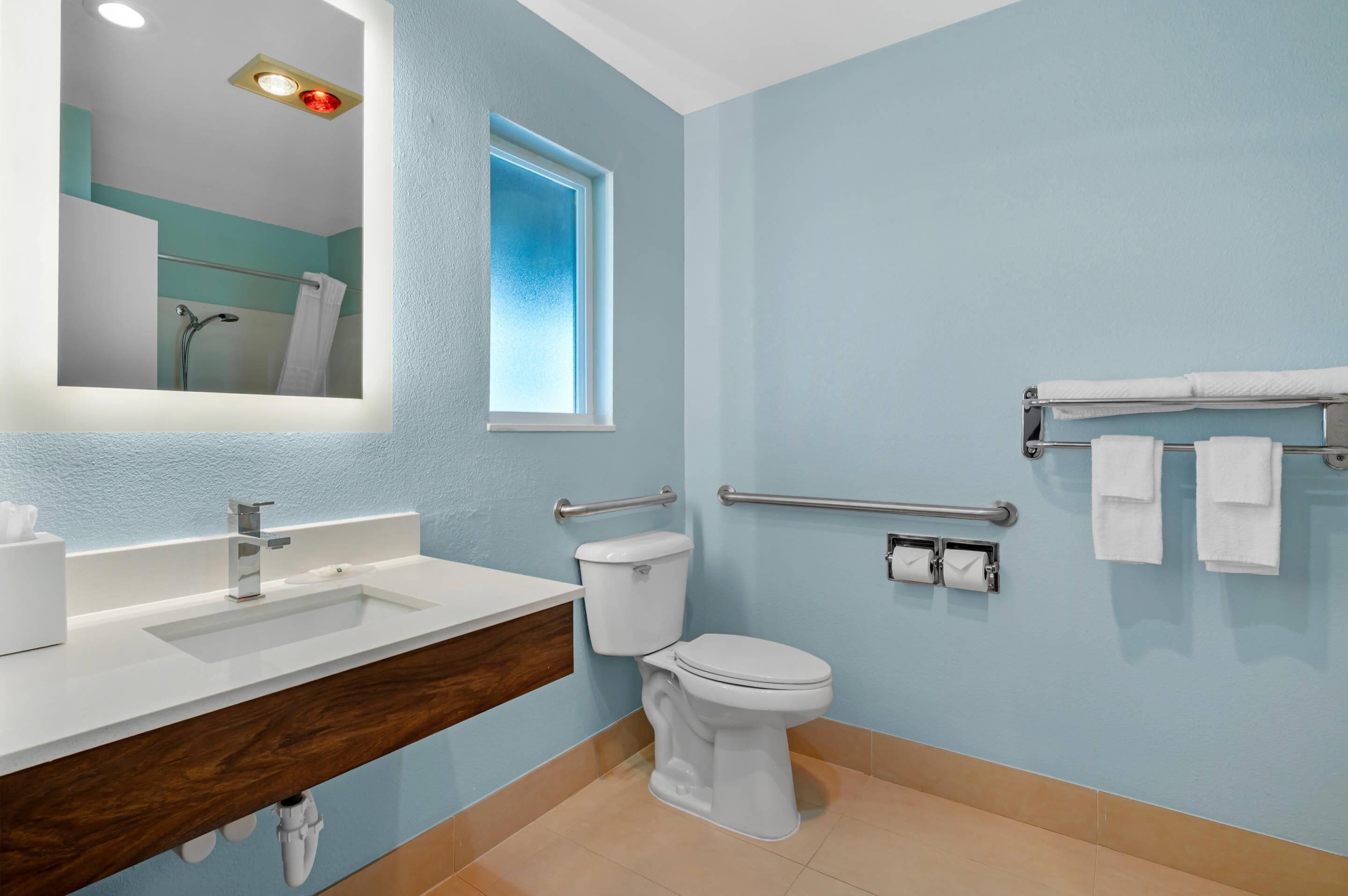 A bathroom with a white sink, a toilet, a window, and a towel rack.