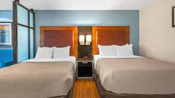 Ein Hotelzimmer mit zwei Betten, einem Nachttisch, einem Holz-Kopfteil und einem Fenster mit Blick.