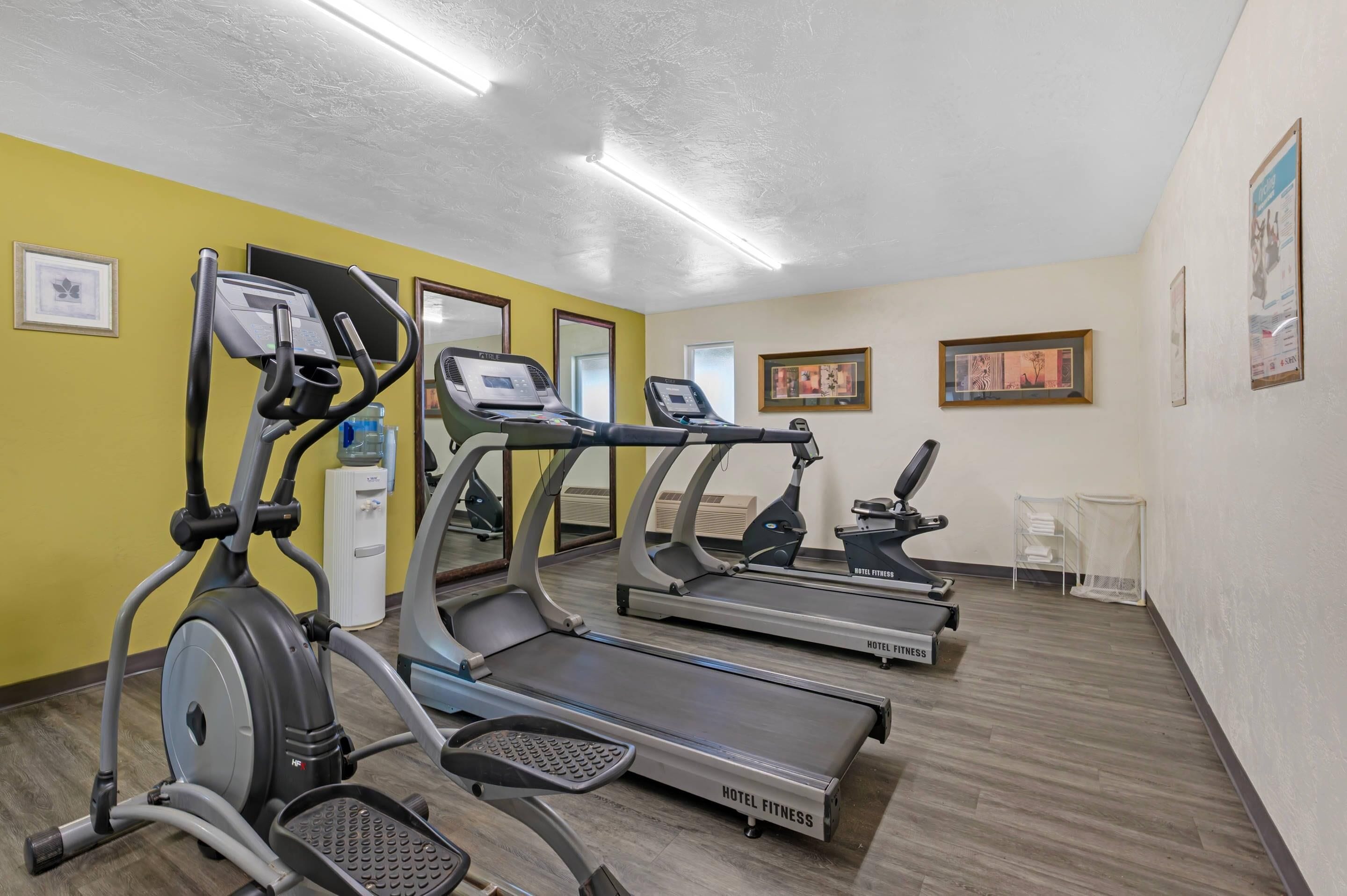 A hotel fitness room with treadmills, a stationary bike, and a water dispenser.