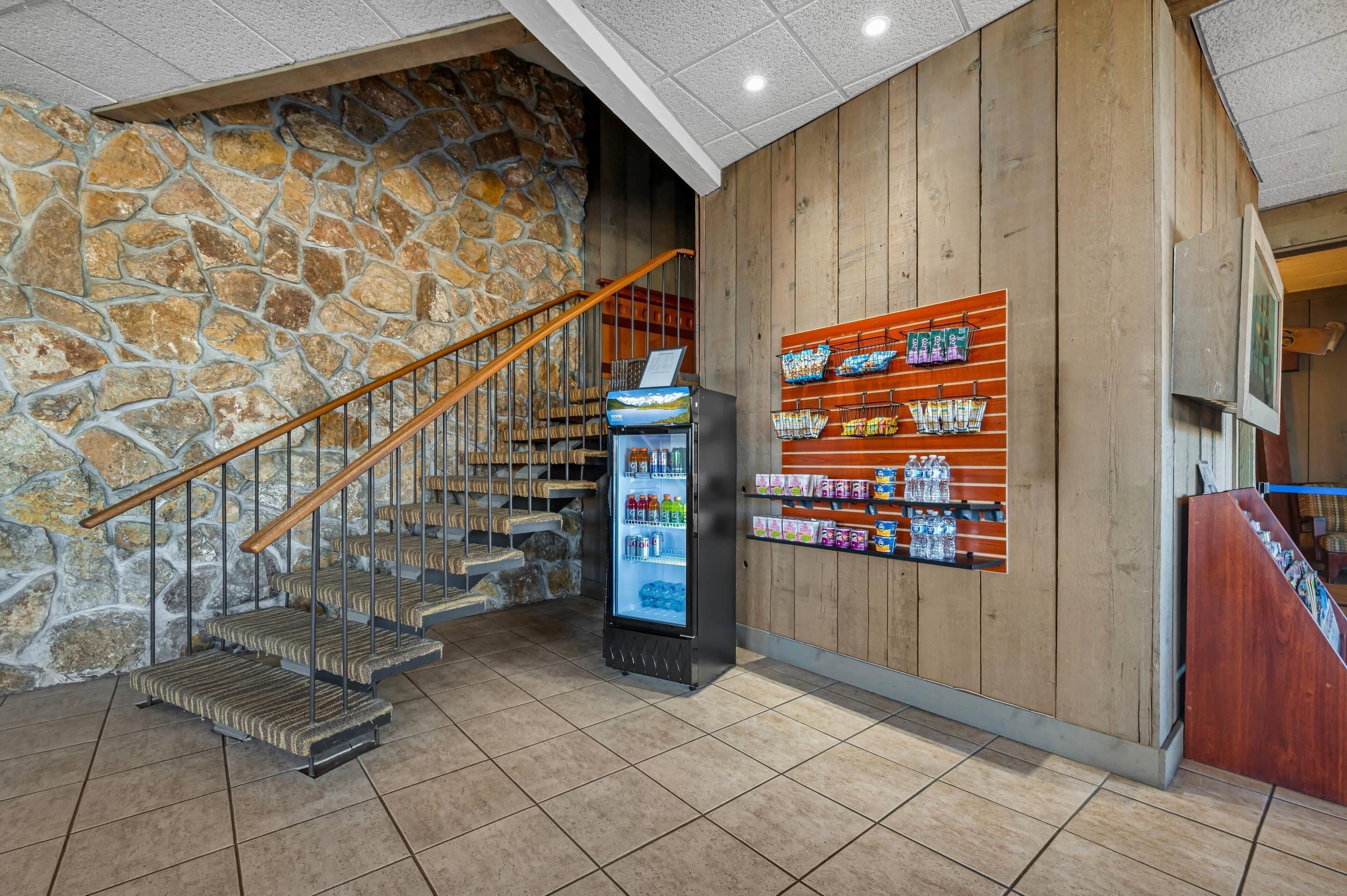 Un escalier avec un mur en pierre, un distributeur automatique et un mur en bois avec des étagères.