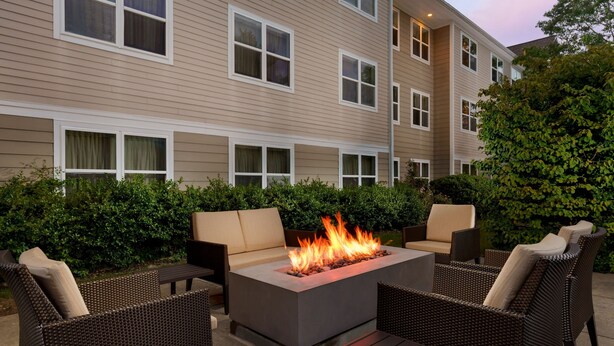 A patio area with a fire feature, outdoor seating, and a building in the background. - Residence Inn by Marriott Boston-Franklin (Franklin)