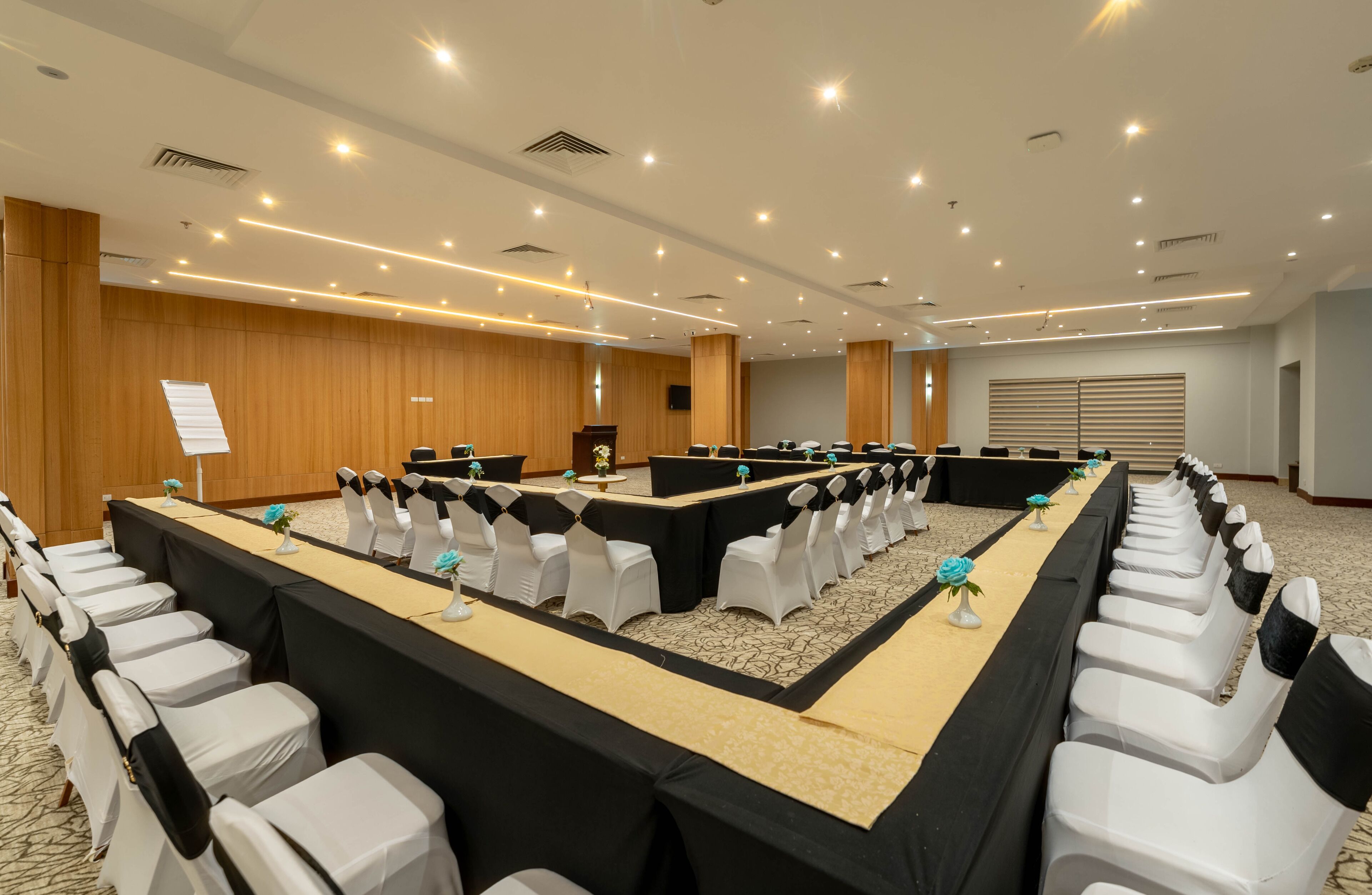 Un salón de conferencias con una mesa larga, sillas blancas y un atril.