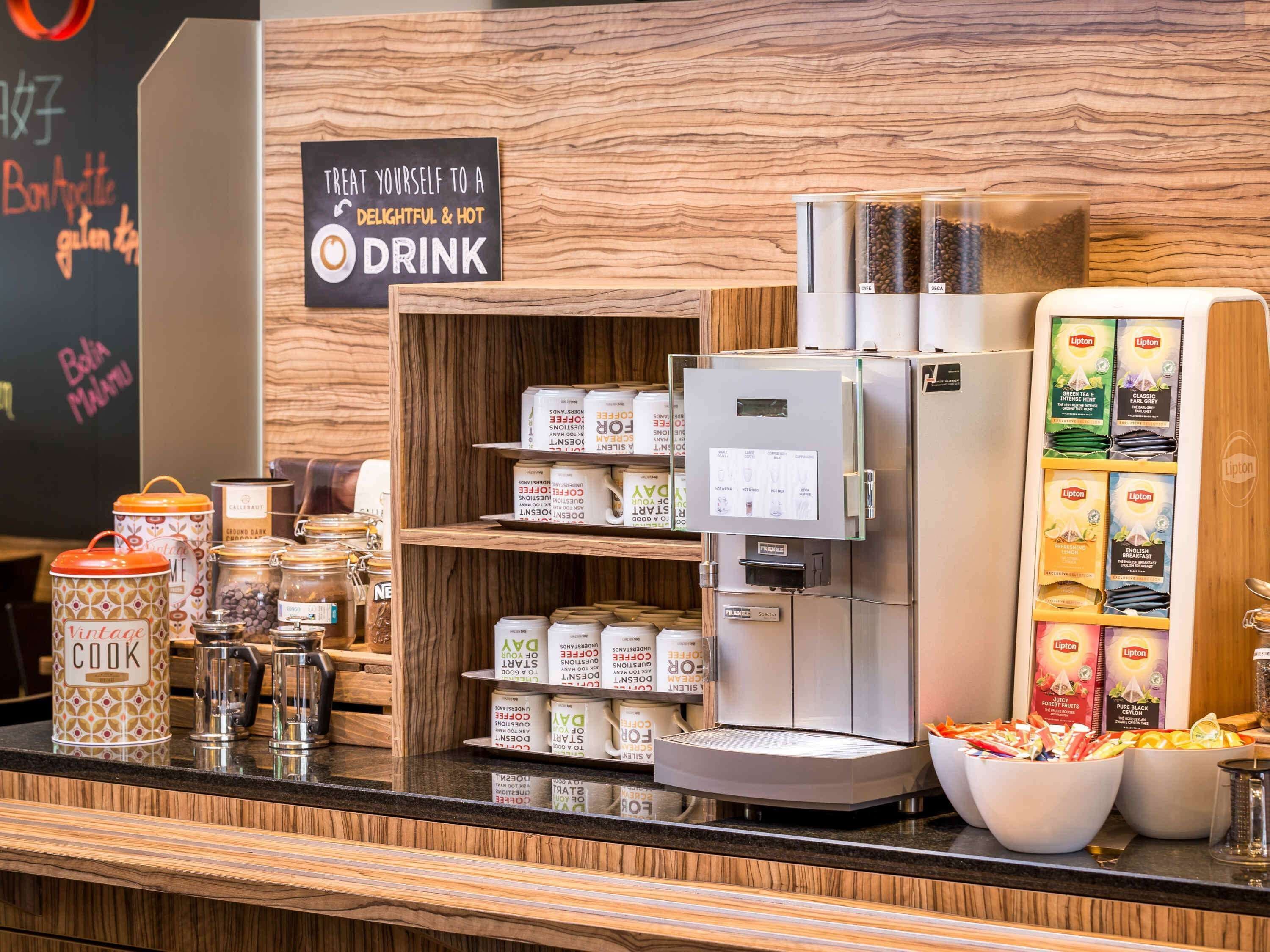 A coffee station with a coffee machine, various coffee pods, and jars of coffee.