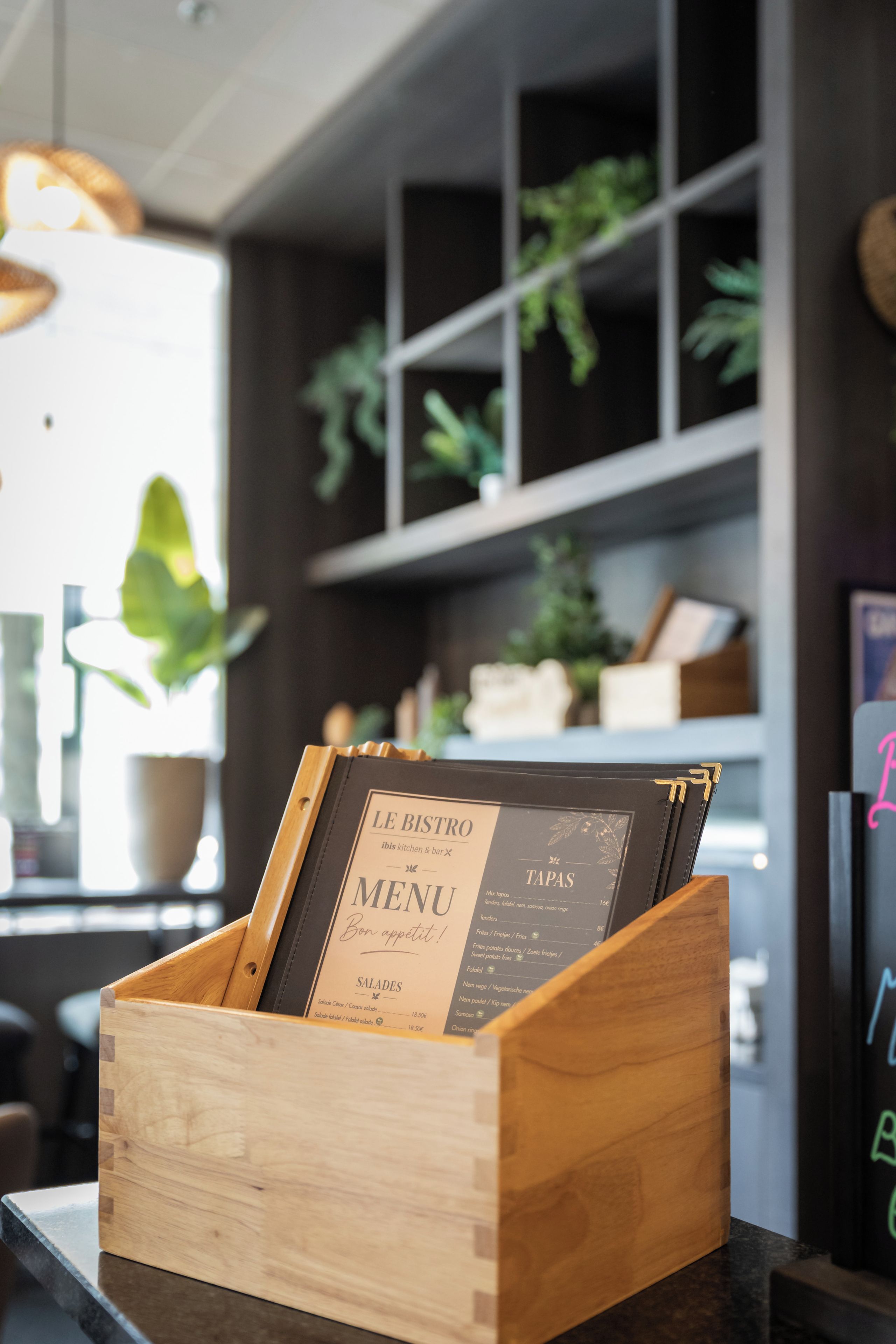 A wooden menu stand with a menu for 'Le Bistro' in a restaurant setting.