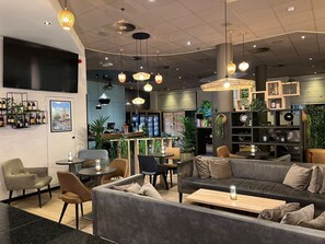 Et moderne interiør med siddeområder, en bar og et stort tv.