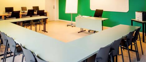 A conference room with a long table, chairs, a whiteboard, and multiple computer monitors.