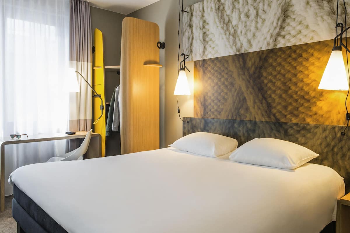 Una habitación de hotel moderna con una cama grande, un escritorio y un armario.