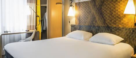 Una habitación de hotel moderna con una cama grande, un escritorio y un armario.