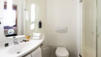 Un baño moderno con un lavamanos blanco, un inodoro y una cabina de ducha de vidrio.