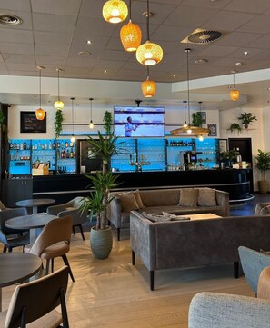 Zona de bar con asientos, una pantalla de televisión y una variedad de botellas en estantes.