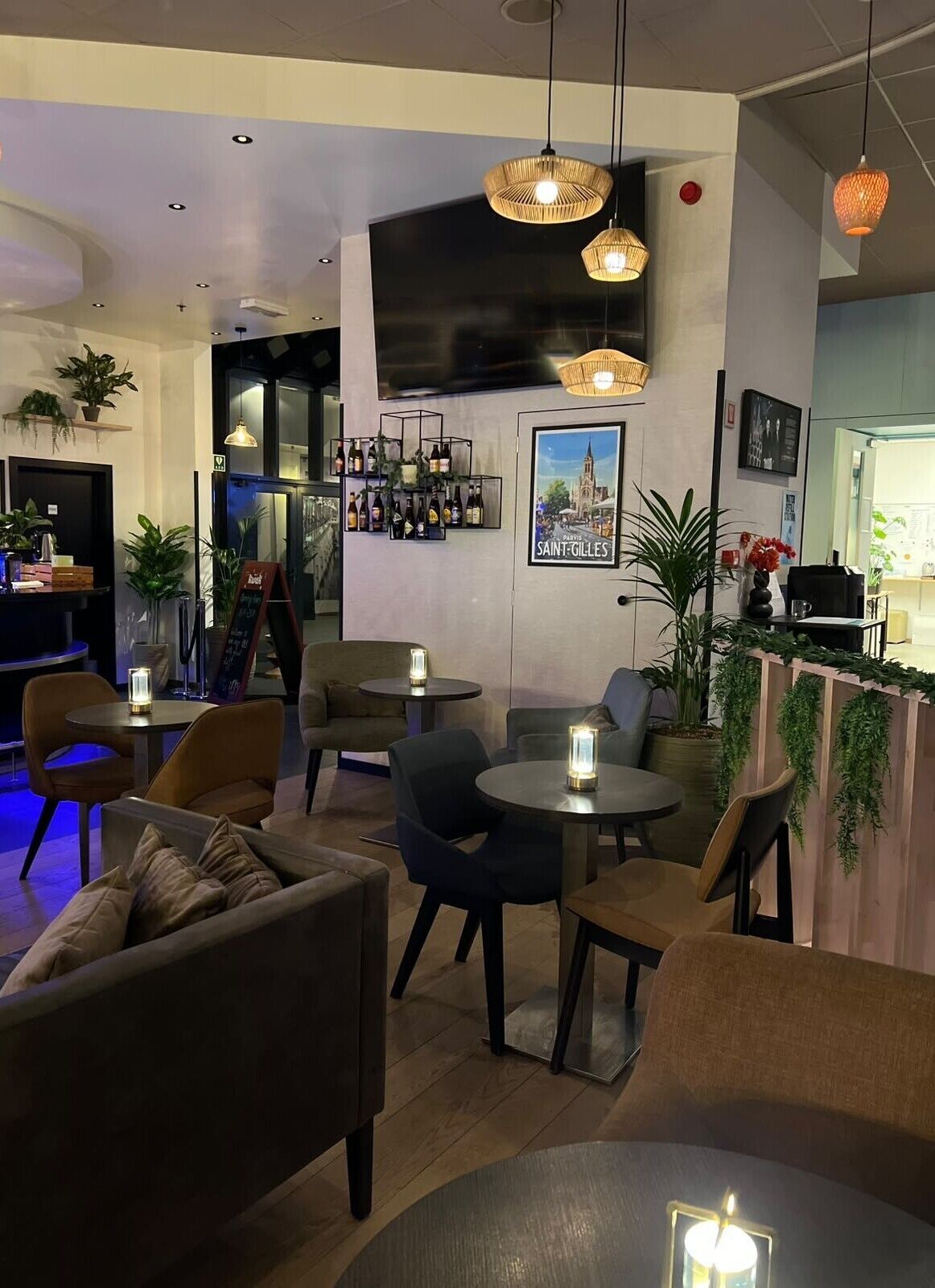Un intérieur moderne avec des tables rondes, des chaises, des luminaires suspendus et un espace bar.