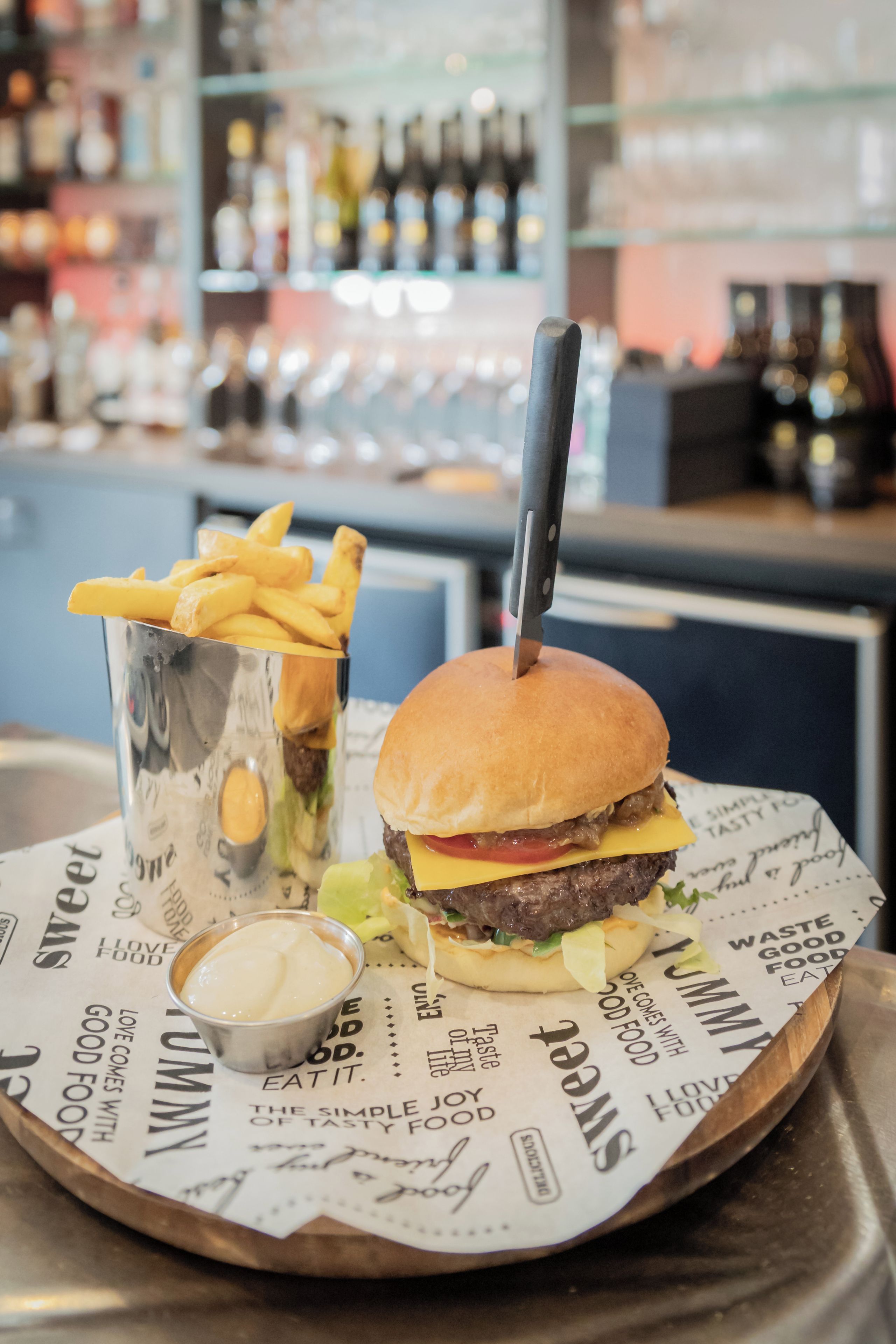 Een hamburger met friet en een drankje op een dienblad, met een mes.