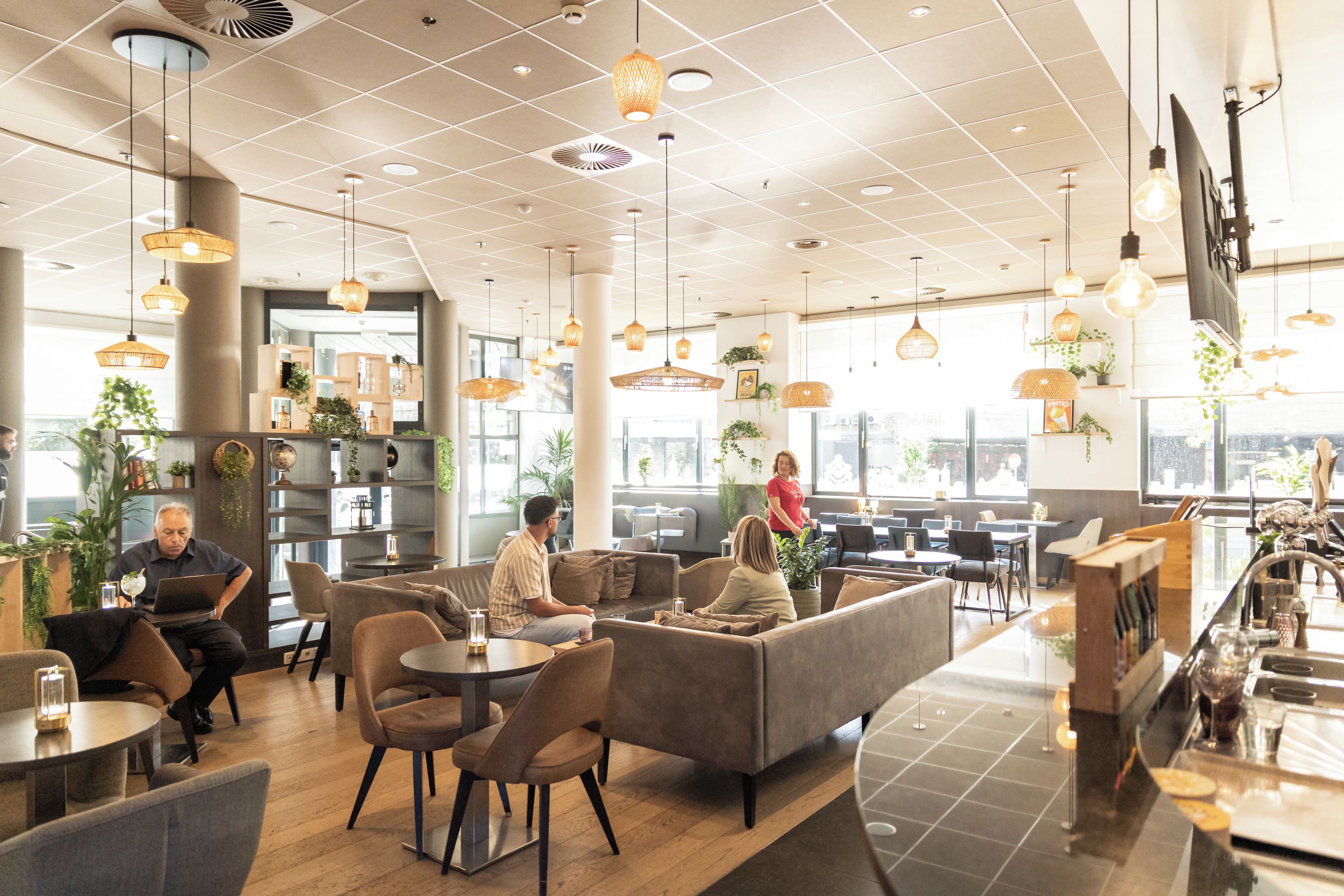 Una cafeteria moderna amb diverses opcions de seients, com taules i sofàs, i una zona de bar amb barra.