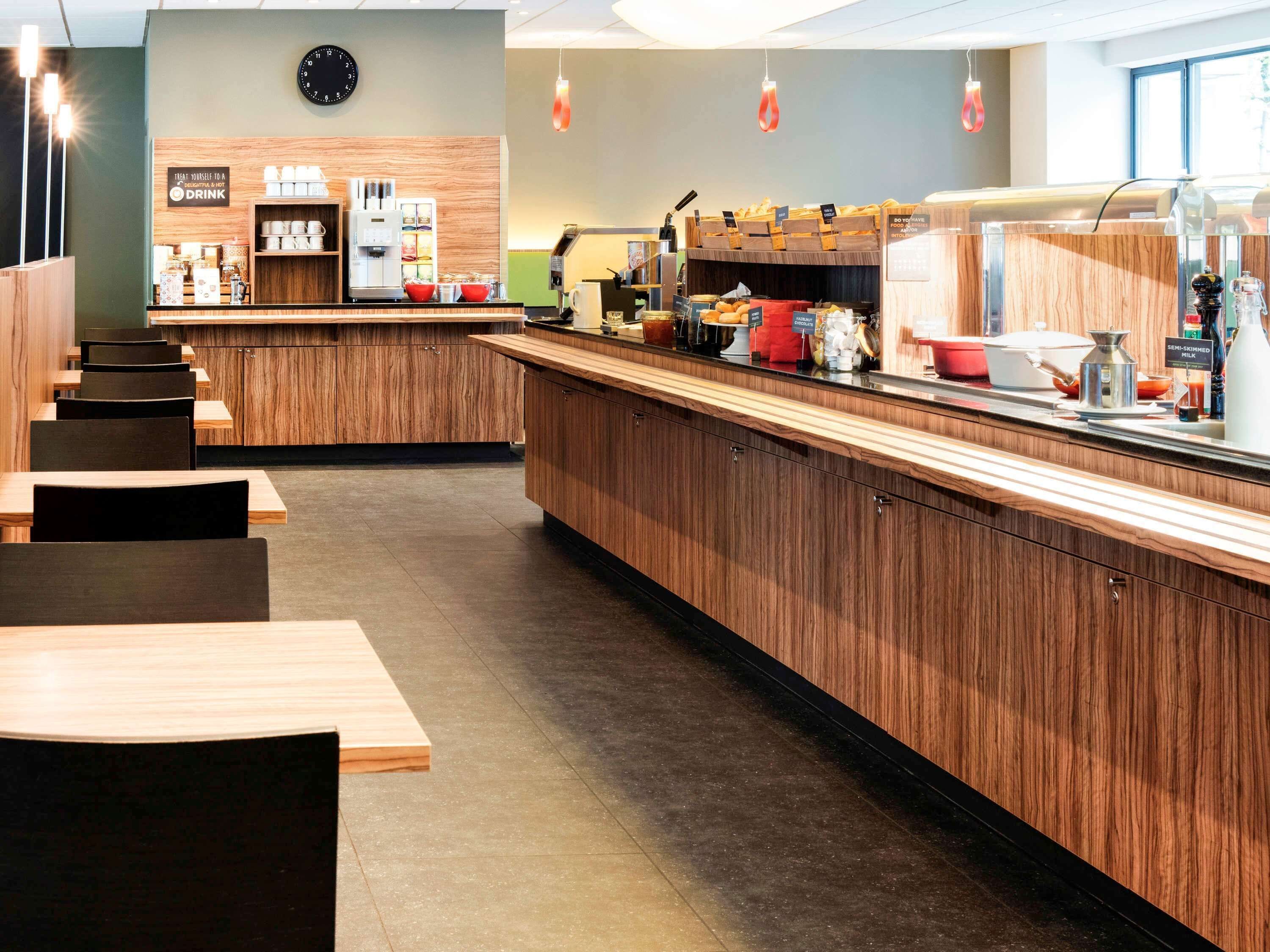 A modern cafe with wooden furniture, a coffee bar, and a clock on the wall.