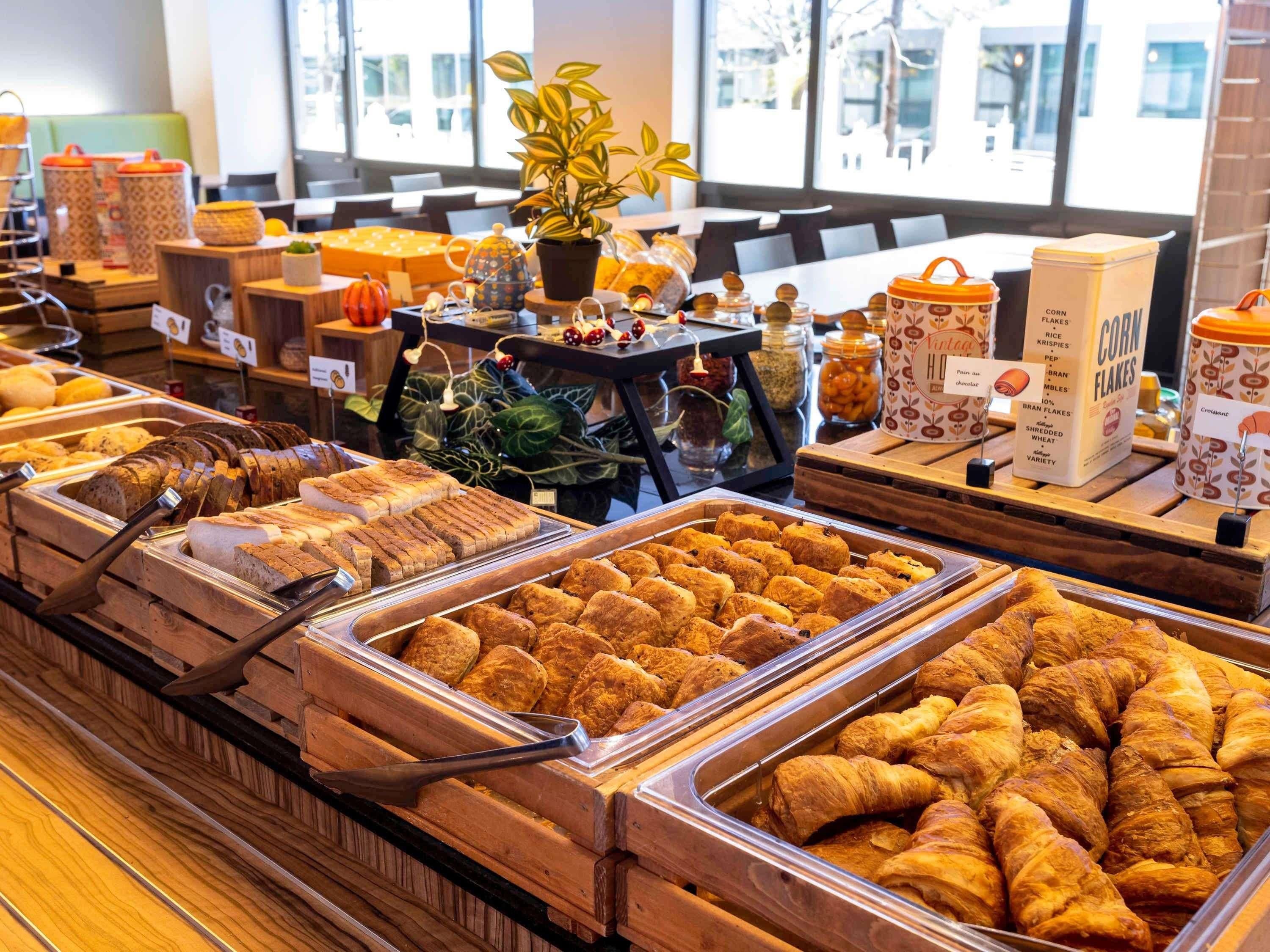 A buffet with various food items, including bread, pastries, and cereals.