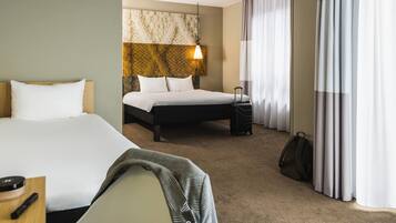 Hotelkamer met twee bedden, een hoofdbord met een lamp, een koffer en een bureau met een afstandsbediening.