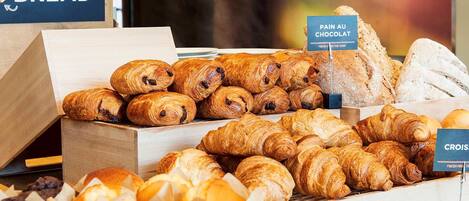 A bakery display with various types of bread and pastries, including croissants and pain au chocolat.