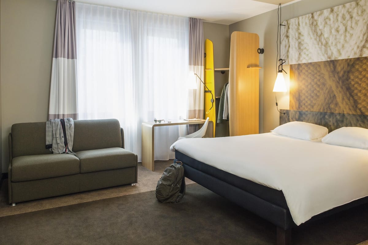 Una habitación de hotel con cama, sofá, escritorio y armario.