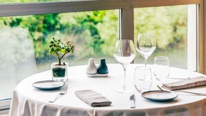 Mesa lista para comer con vistas al exterior, rodeada de vegetación.