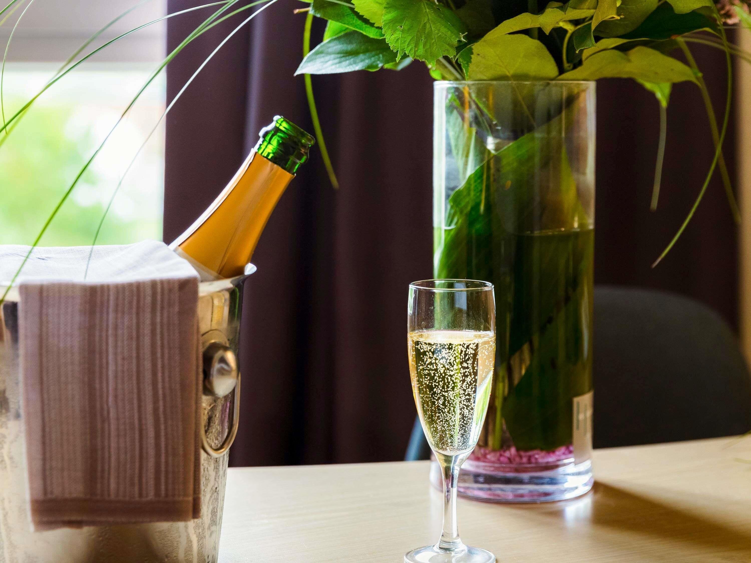 A bottle of champagne, a glass of champagne, and a vase with a plant.