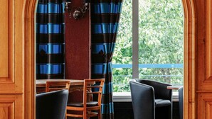 Una habitación con una mesa y sillas de madera, un suelo con diseño y vistas a la vegetación exterior.