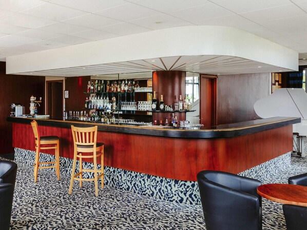 A bar area with a curved counter, wooden chairs, and a patterned carpet. - Mercure Nevers Pont de Loire (Nevers)