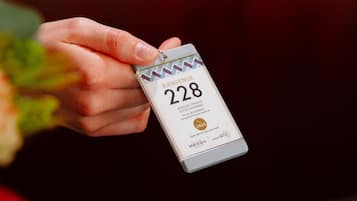 En hånd holder et kort med tallet 228.