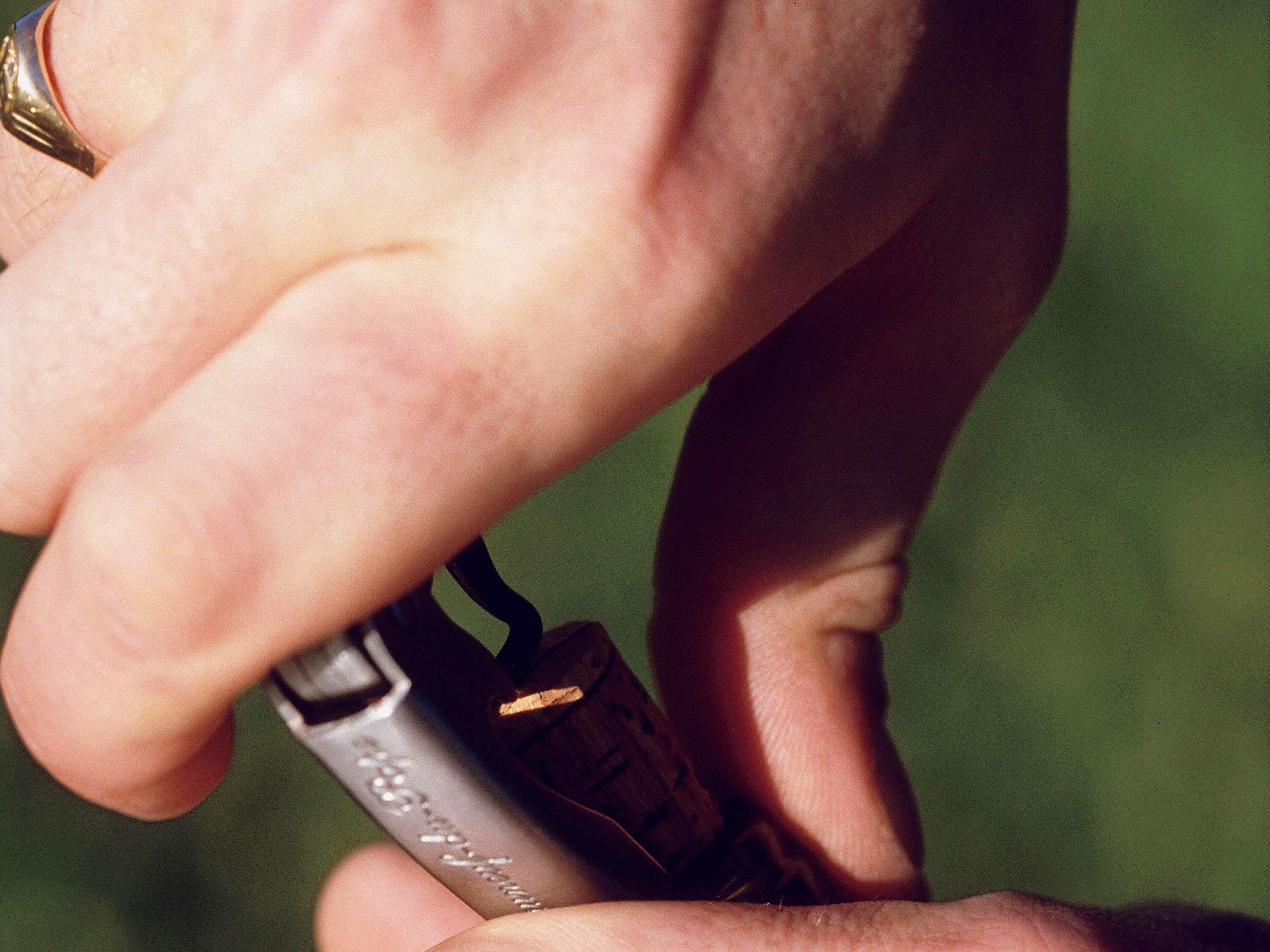 Une main tenant un briquet sur lequel on peut voir du texte.